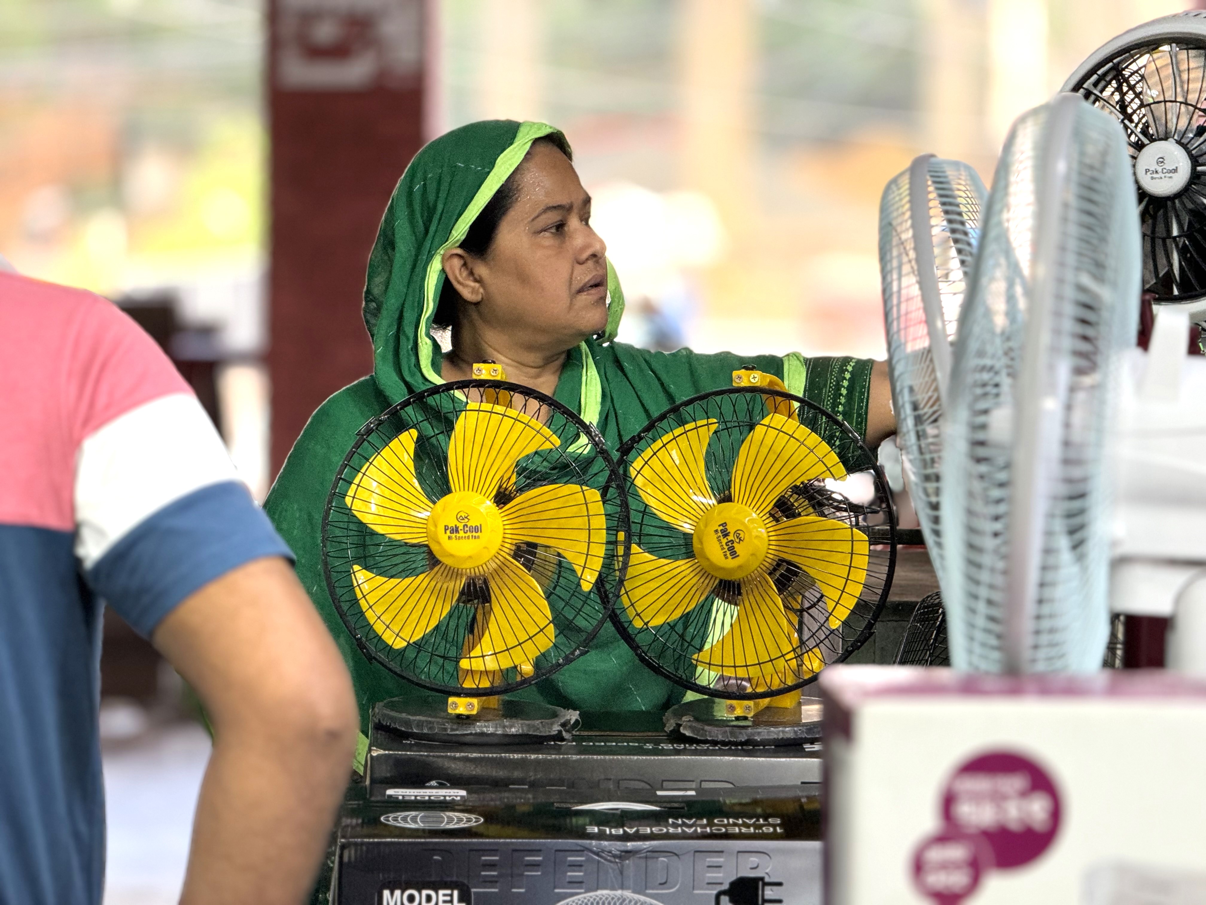 Farida Begum, a housewife in Dhaka, Bangladesh, looks at buying a fan to help with the extreme heat, June 2024. Mosabber Hossain/HERA