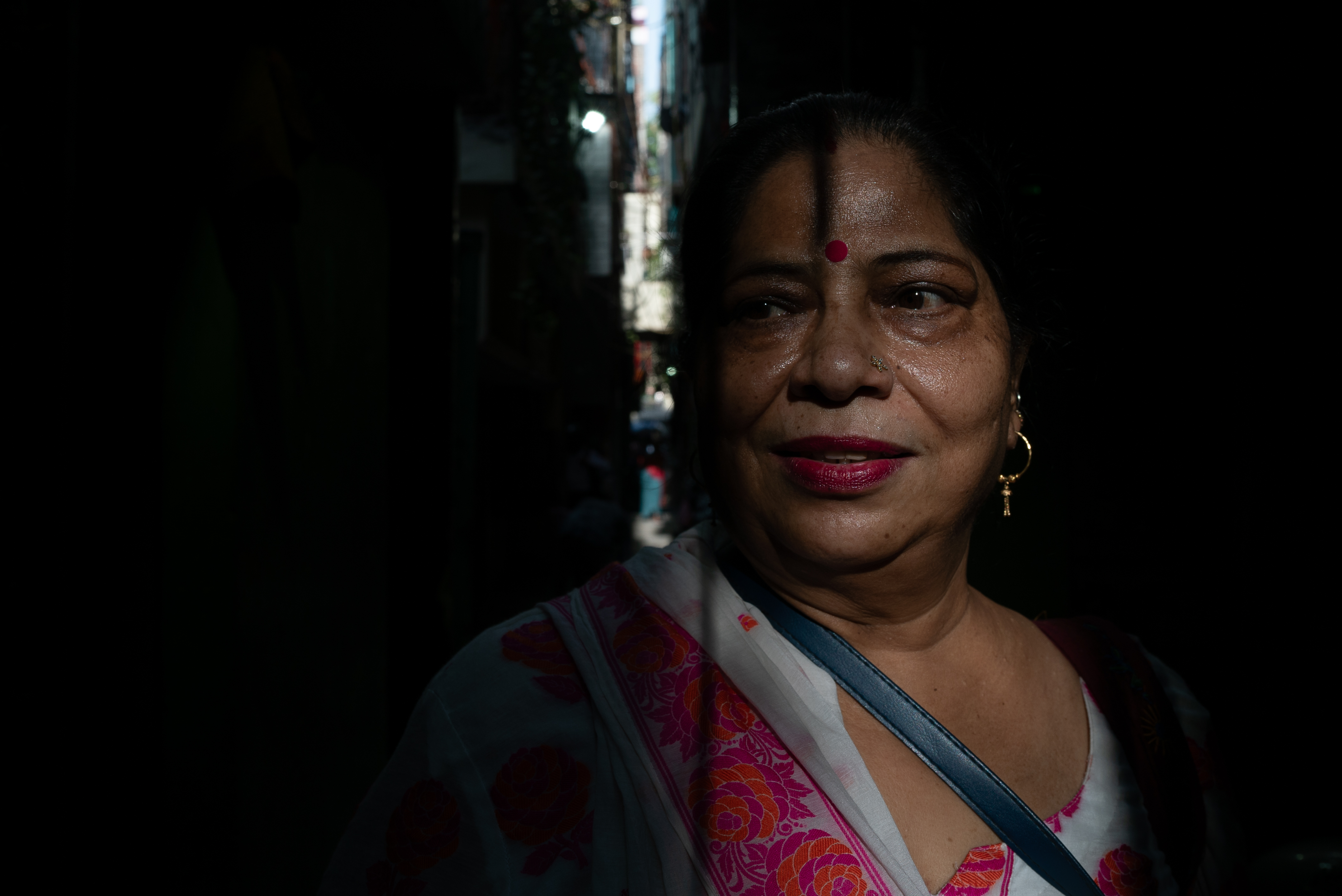 Asha Devi, 56, sweats as she navigates a narrow lane in New Delhi’s Ambedkar Nagar during a heatwave, June 2024, India. (Photo credit: Bhumika Saraswati)