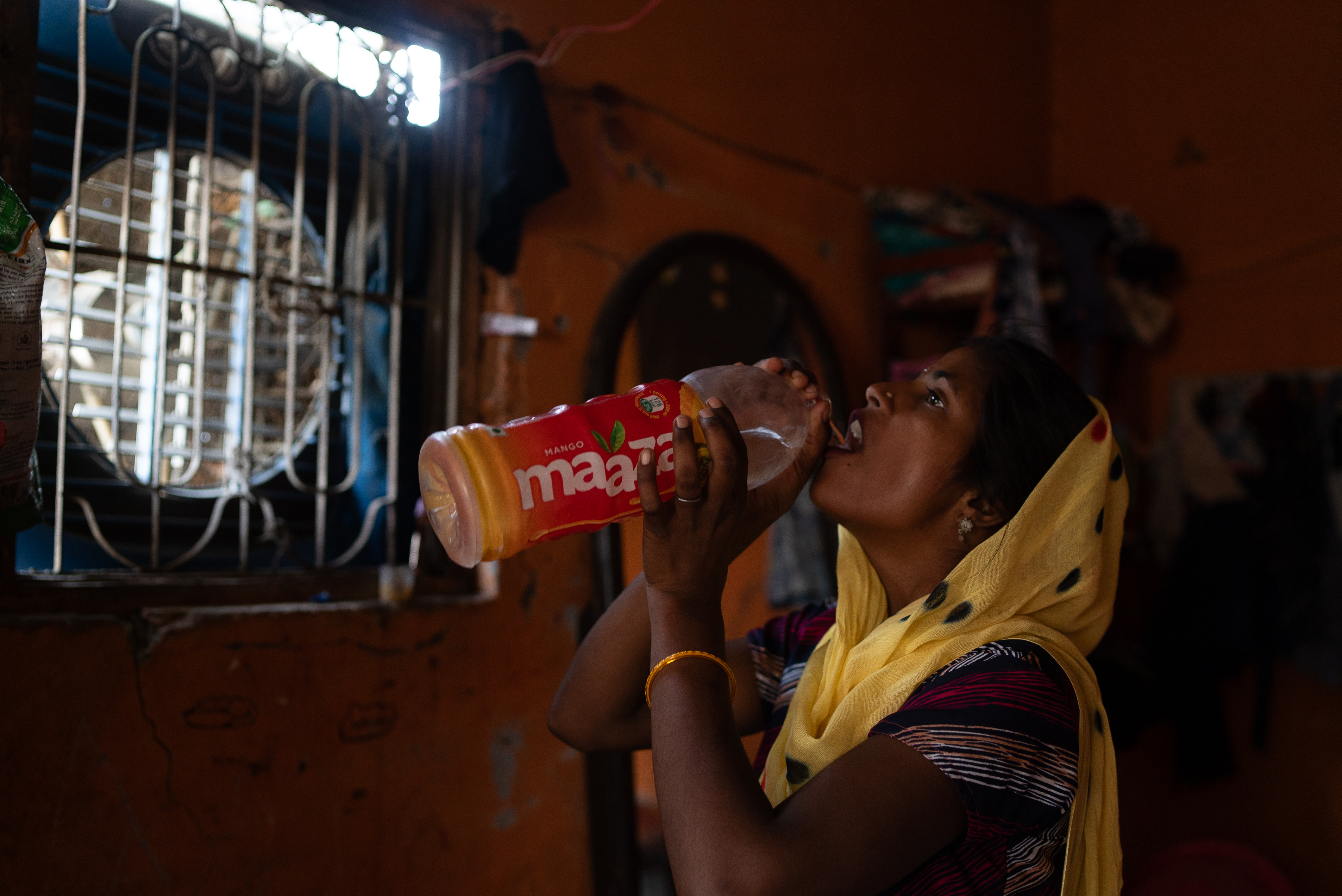 A woman drinks water stored in an old beverage bottle amid a heatwave in New Delhi, India, June 2024. (Photo credit: Bhumika Saraswati)