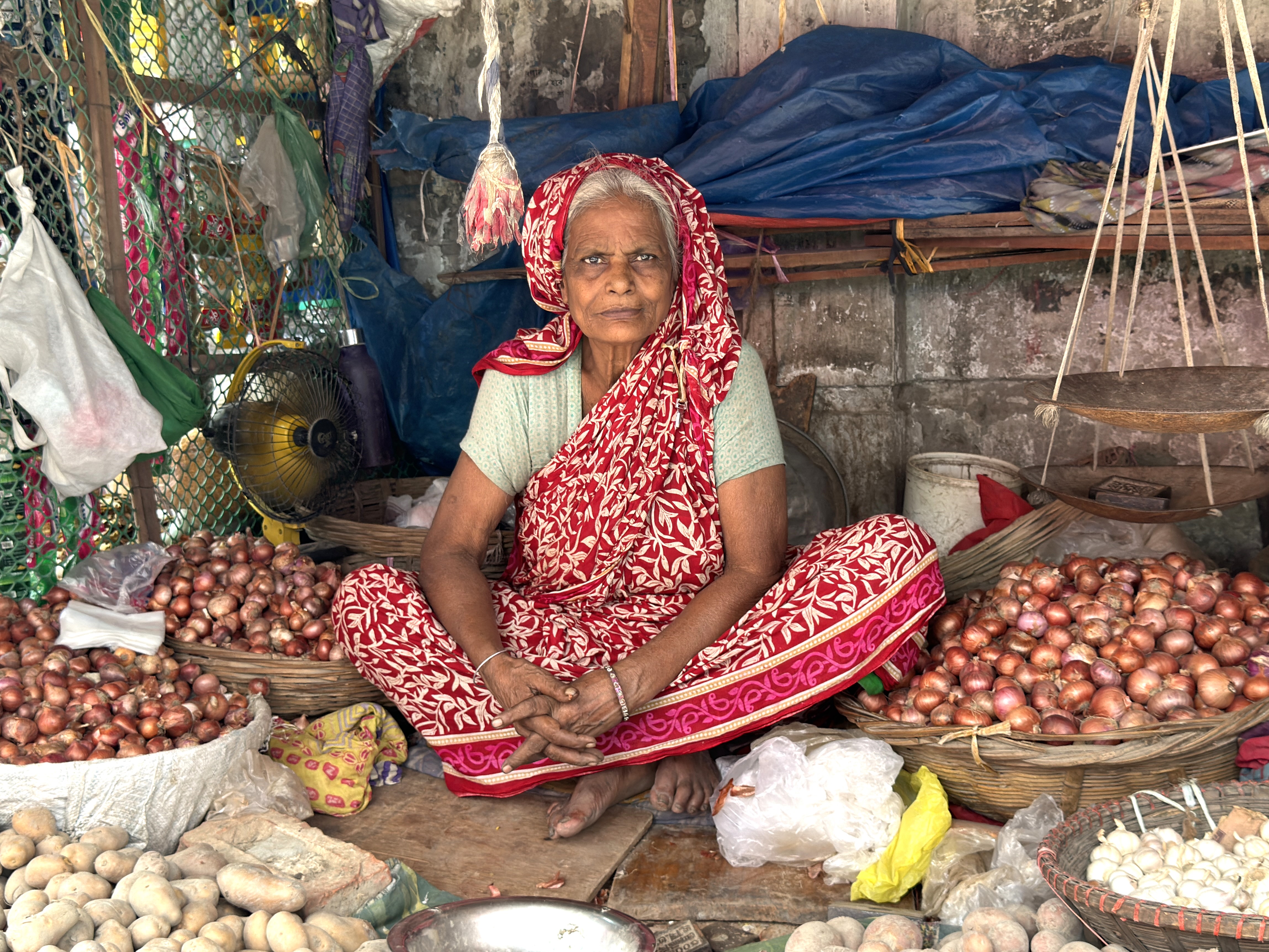 A woman sits in her stall in a Dhaka market on a hot day in August 2024. Credit: Mosabber Hossain