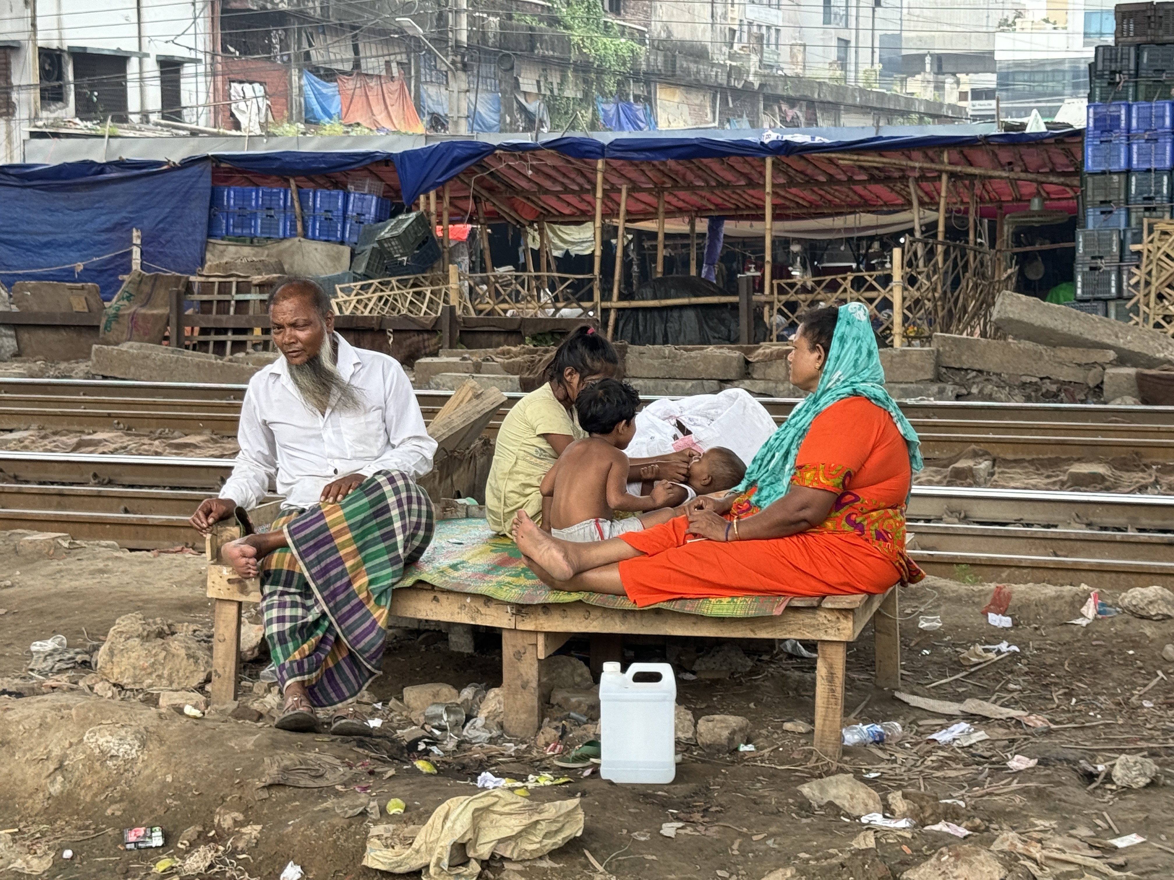 A family who live in a room in Dhaka’s Karwan Bazar slum that becomes suffocating in hot periods rest outside in an effort to cool themselves in August 2024. Credit: Mosabber Hossain