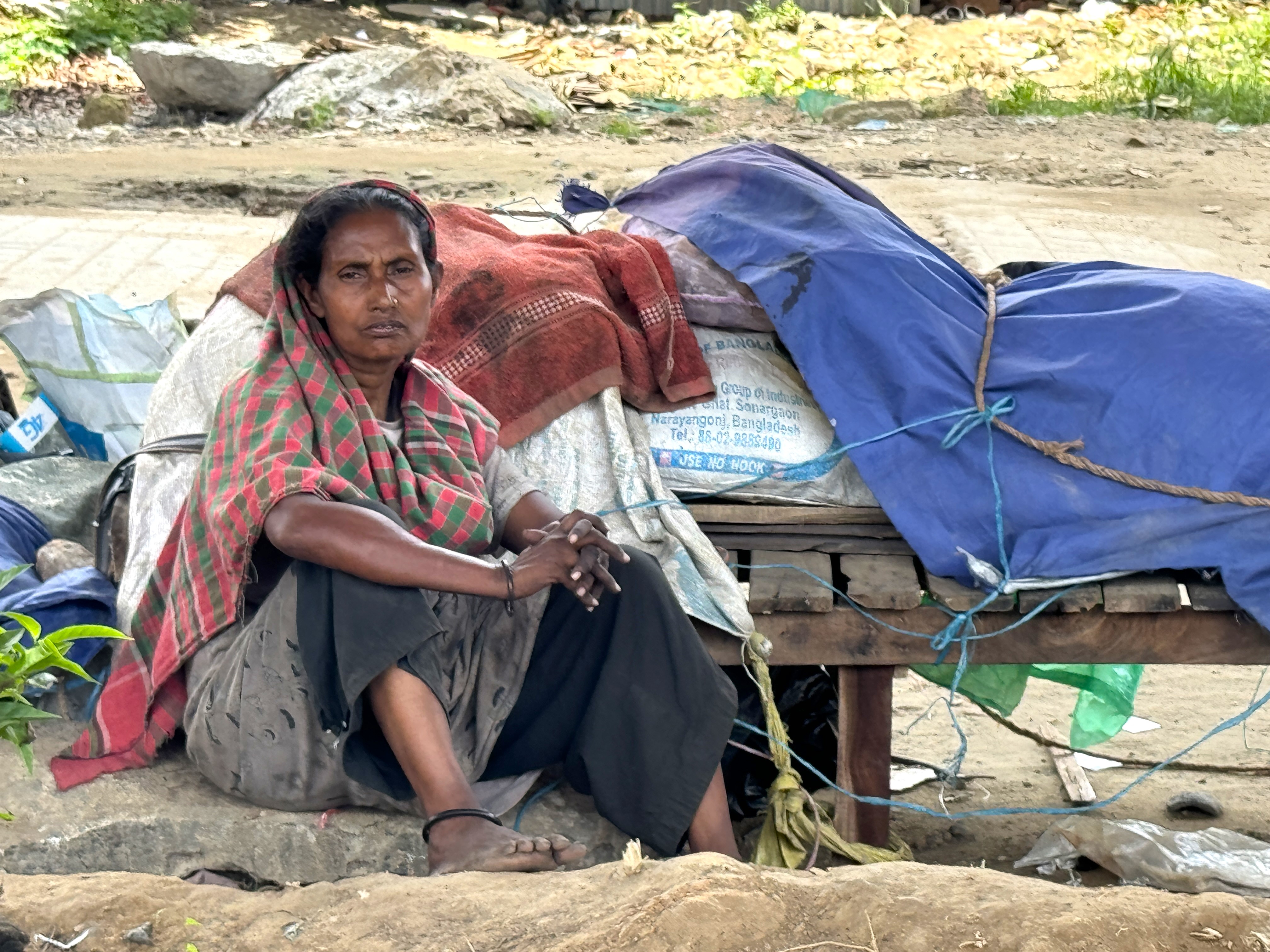 A migrant woman whose home in Dhaka’s Karwan Bazar slum lacks electricity seeks relief outside on a hot day in August 2024 in the Bangladeshi capital. Credit: Mosabber Hossain