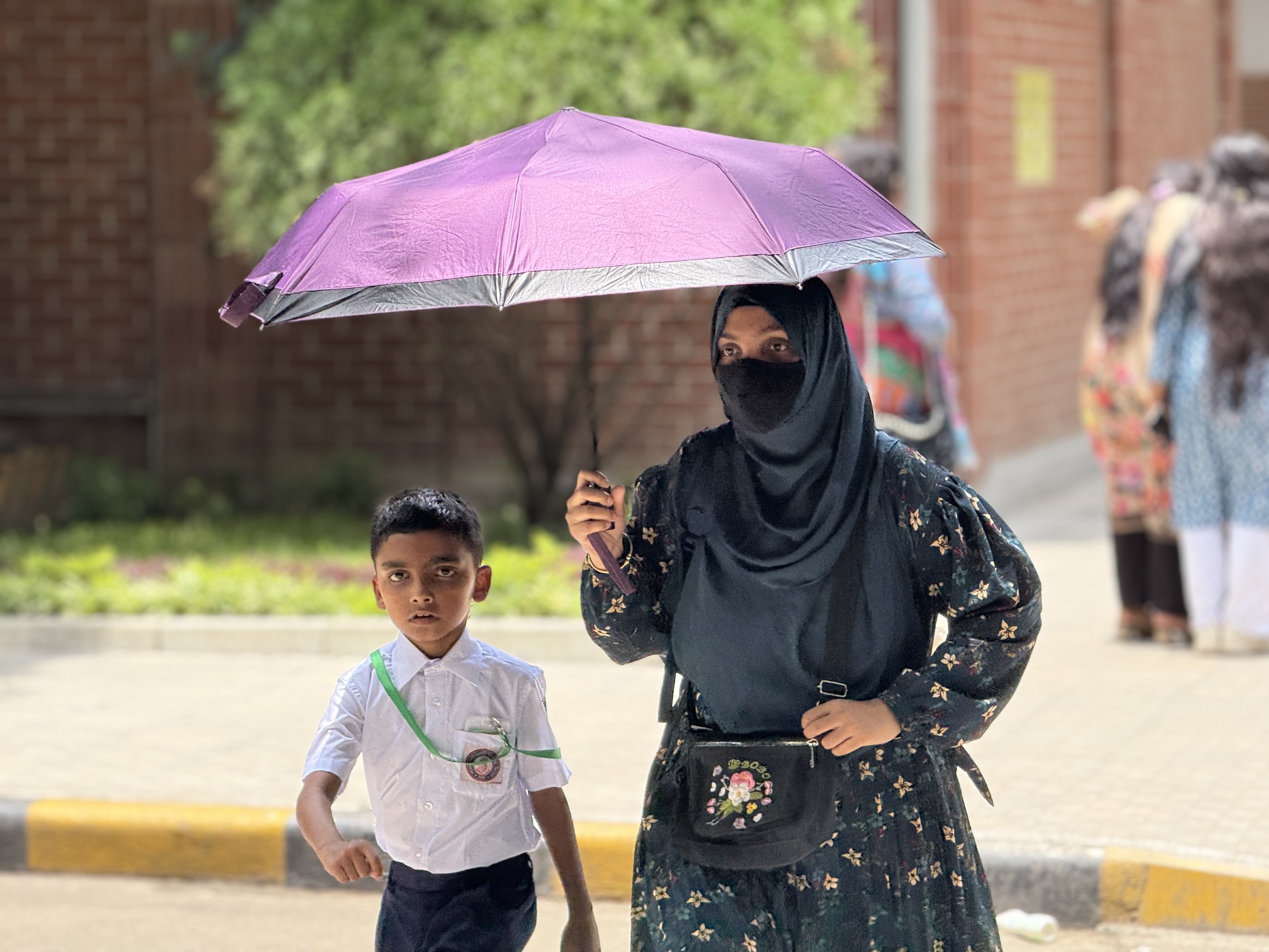 Sumona Sarmin and her son shelter from the sun under an umbrella on a hot walk home from school in Dhaka, Bangladesh, on May 29, 2025. Mosabber Hossain/Climate Resilience for All