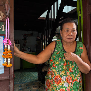 Bhu Pha, 69, stands in her doorway in Khlong Toei, Bangkok, Oct. 10, 2025. Climate Resilience for All/Laurie Goering