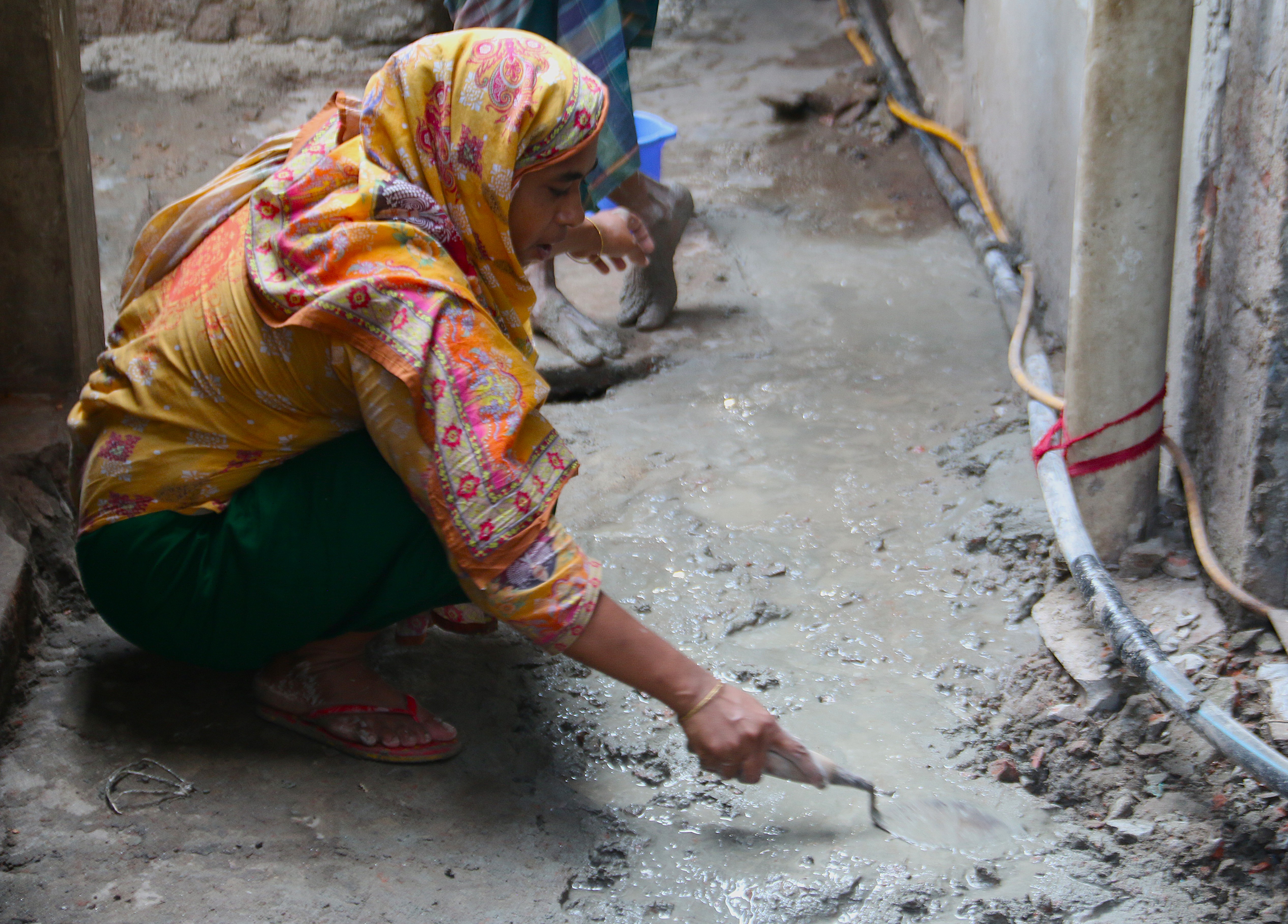Construction worker Anjuman Ara smoothes concrete as part of her work in Kallanpur, in Dhaka, Bangladesh, October 13, 2025. Climate Resilience for All/Tanvir Ahmed