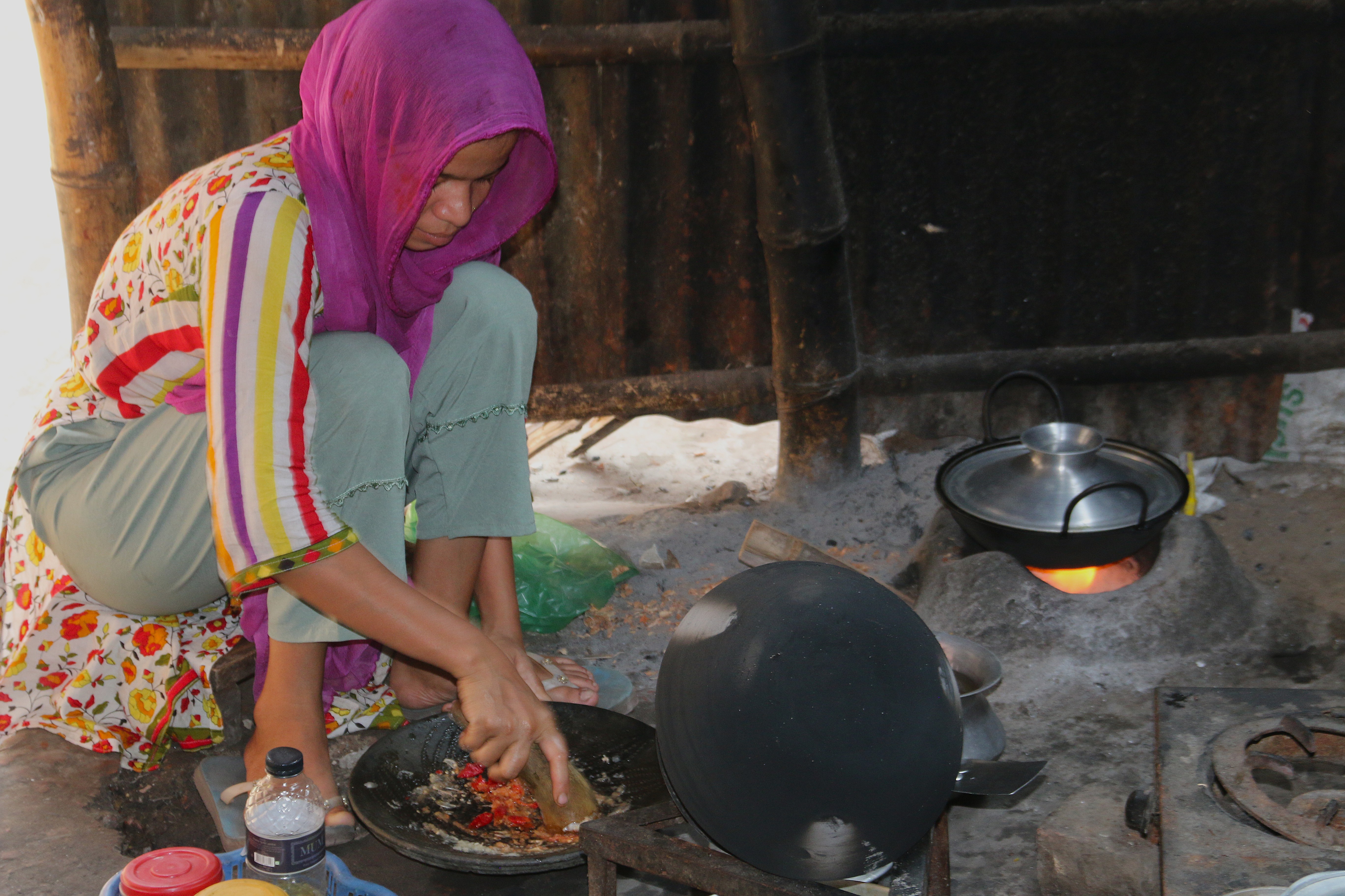 Tahera Begum, a garment worker, cooks for her family on a traditional wooden stove. Balancing household chores with job stress leaves her fatigued and anxious, she said. Kallyanpur, Dhaka, October 12, 2025. Climate Resilience for All/Tanvir Ahmed