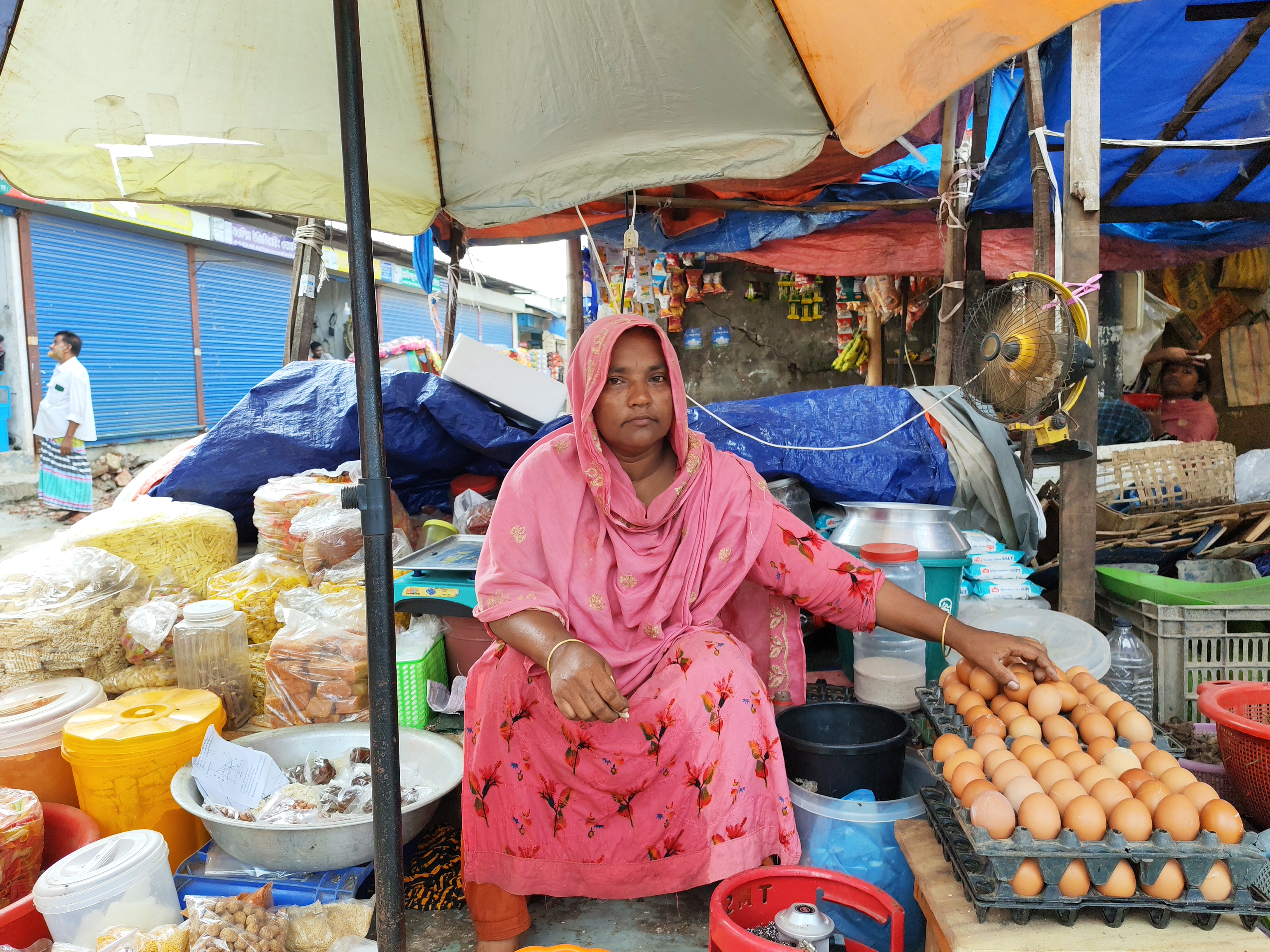Najnin Begum sells food to low-income people and day laborers in the Mirpur area of Dhaka, Bangladesh, in October 2025. Worsening heat has forced her to buy a fan using her savings, and its use has added an extra 500 taka ($4) to her monthly electricity cost. Climate Resilience for All/Tanvir Ahmed